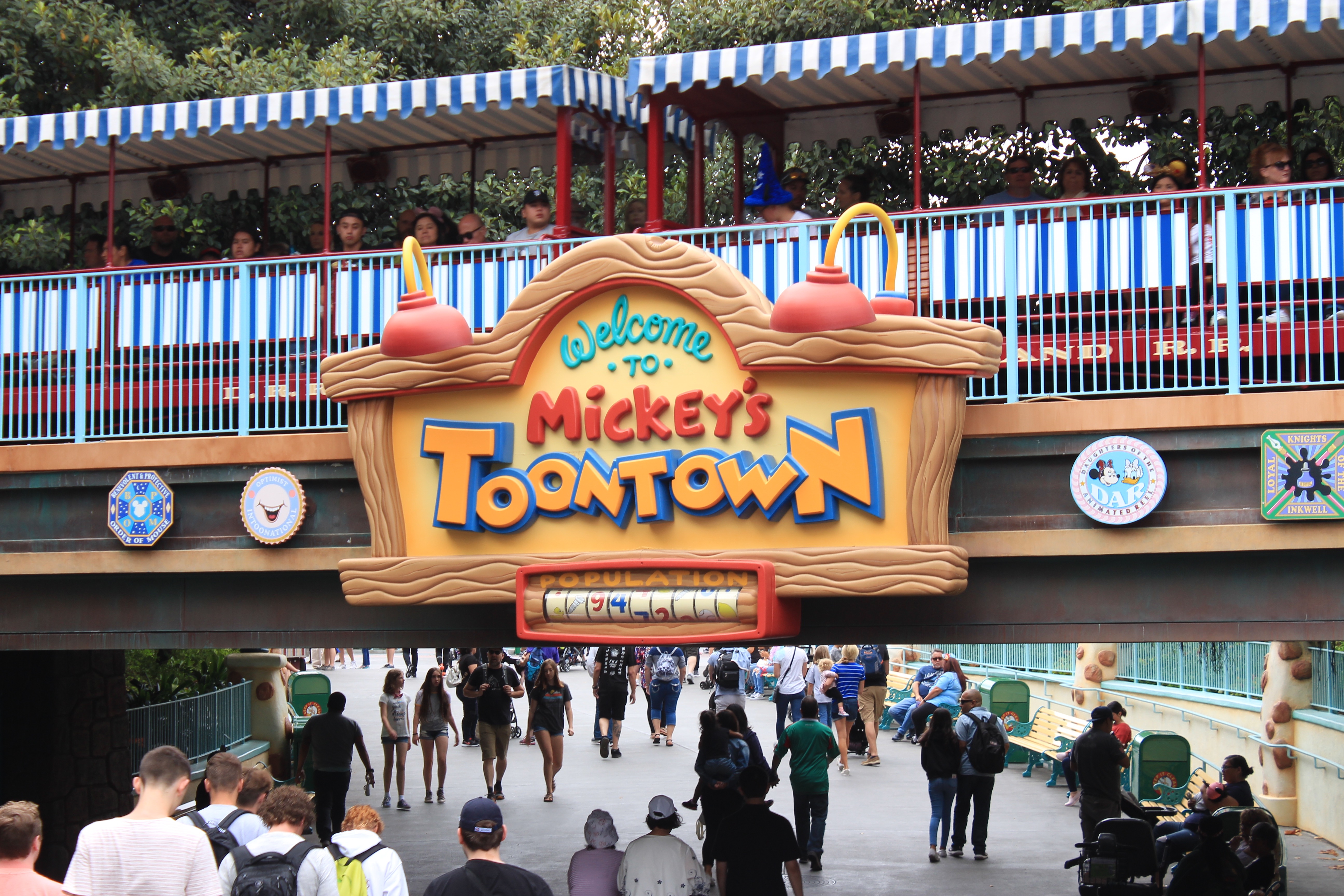 Sign over a bridge underpass stating "Welcome to Mickey's Toontown" with the Disneyland Railroad passing overhead.